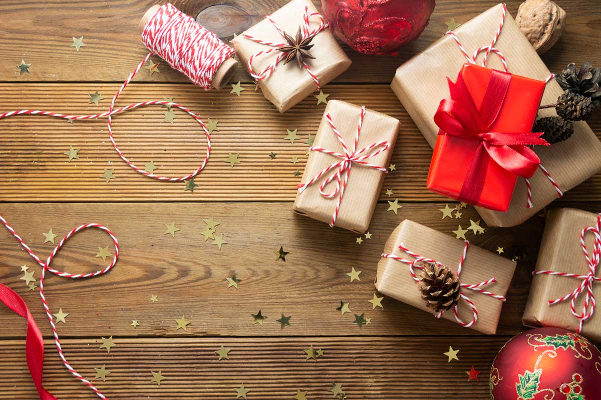 Christmas Background With Gift Boxes Wraped In Craft Paper Over Wooden Table Prepared For Celebrating Festive Holiday Season. Copy Space.